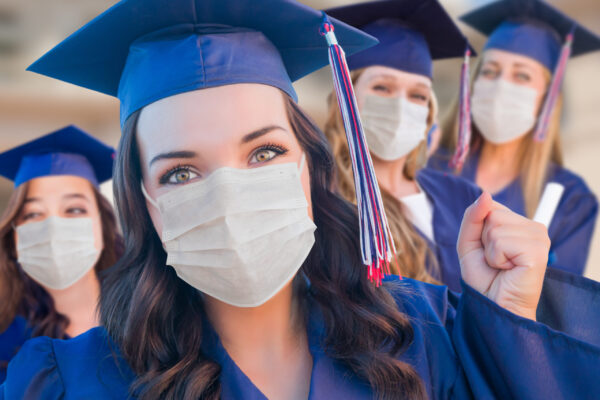 Several Female Graduates in Cap and Gown Wearing Medical Face Masks.